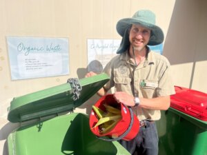 Headline Lone Pine Koala Sanctuary worker in front of recycling bin